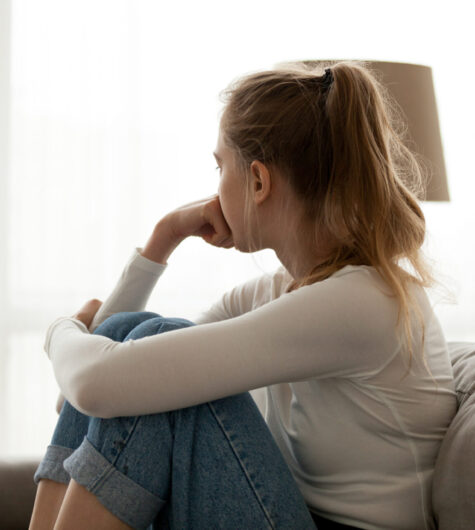 Upset woman sitting on couch alone at home