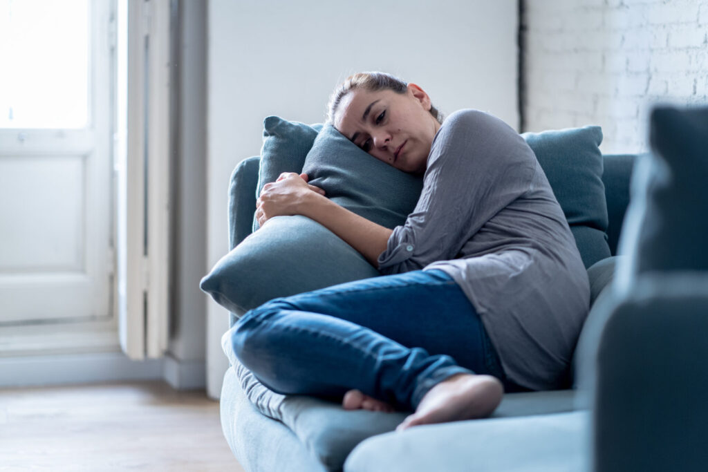 Young attractive latin woman lying at home living room couch feeling sad tired and worried suffering depression in mental health, problems and broken heart concept