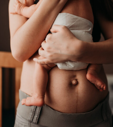 Closeup of a new mom standing in a dimly lit nursery holding her newborn baby
